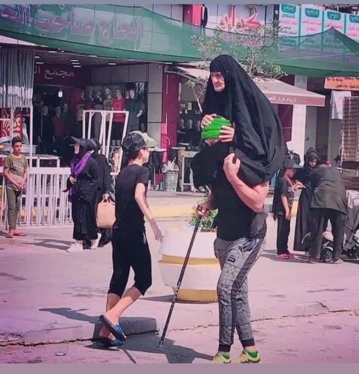 زائر عراقي يحمل أمه على رأسه مشياً على الأقدام إلى كربلاء المقدسة